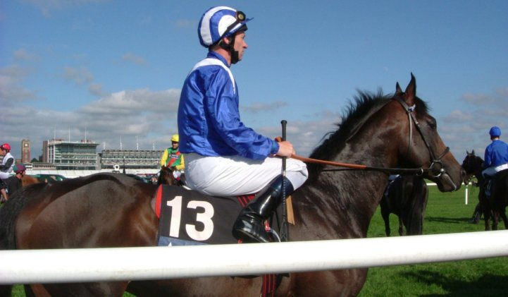 Jockey with blue outfit sat on race horse